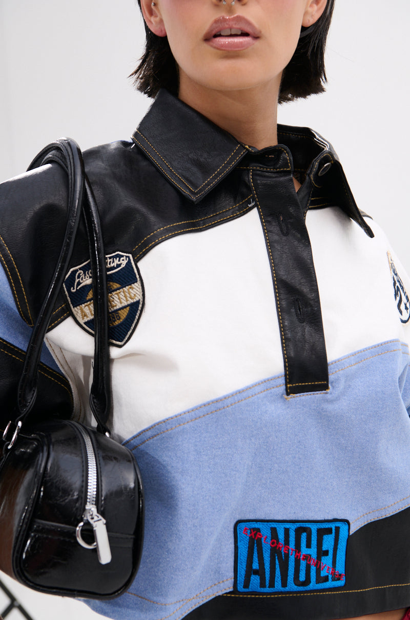 A woman wears the GUESS WHAT STRIPE COLLARED BLOUSE and carries a small black handbag over her shoulder. The cropped photo captures her bold streetwear vibe from her lips to her torso.