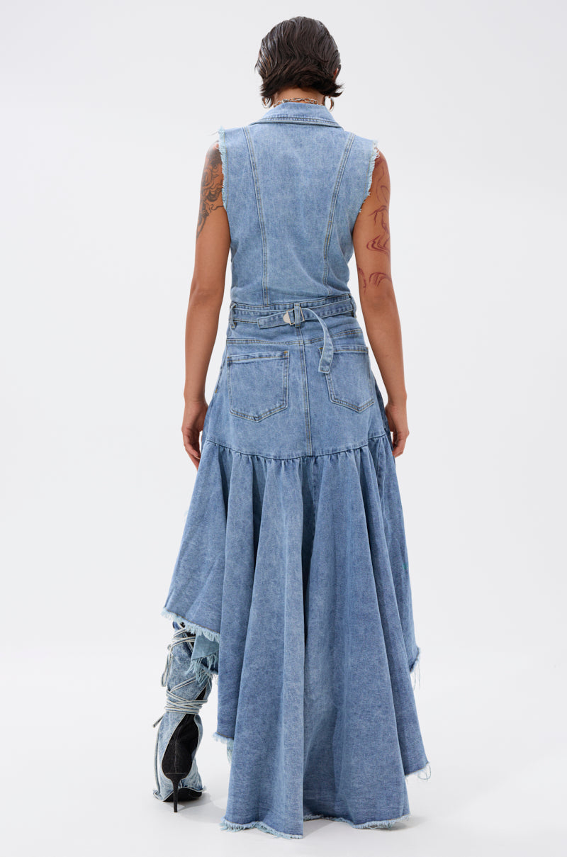 A person with short hair and arm tattoos wears the READ IT AND WEEP DENIM MINI DRESS—a sleeveless, light-wash mini with a belted waist, flared skirt, and ruffled hem—standing with their back to the camera against a plain background.