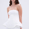 A woman with long, wavy brown hair models the IM TOO GOOD FLARE BELT, a strapless white corset top with a peplum silhouette and matching white pants, standing against a plain light background.