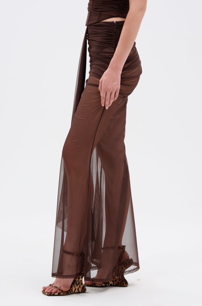 A person wears the SHAKE IT FOR ME GIRL MESH MAXI SKIRT, a high-rise mesh maxi skirt with ruched details, paired with brown strappy sandals featuring a leopard print platform heel, standing against a plain white background. 3