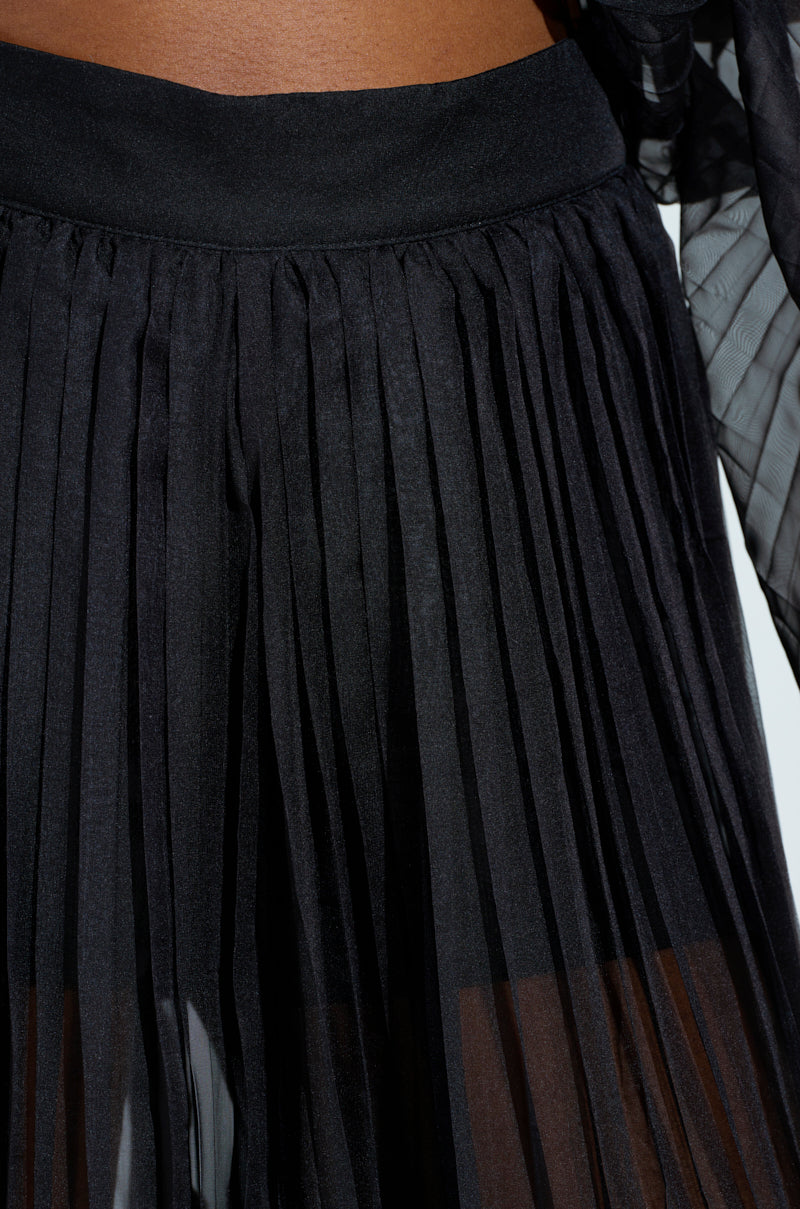 Close-up of THE JULIE TROUSER in black with a high-rise waistband. The sheer fabric offers a layered texture, and part of a dark-toned garment appears at the top against a plain background.