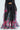 Dressed in THE JULIE TROUSER with flowy, wide-leg chiffon pants featuring a black base and vibrant pink floral pattern, paired with a sheer top adorned with long, draping sleeves, this outfit radiates a stylish and elegant look.