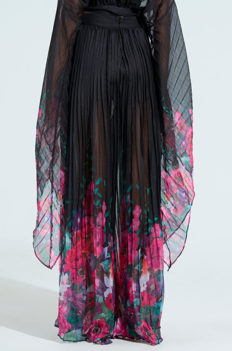 Introducing THE JULIE TROUSER: a flowing, sheer design featuring a pleated black waist that seamlessly transitions into vibrant floral patterns of pink, purple, and green hues. With wide, cape-like details and an elegant drape reminiscent of a wide-leg silhouette.