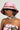 A person wearing a YOU CANT SEE ME CAMO BUCKET HAT and strapless top, complemented by sleek sunglasses and large hoop earrings. A chunky metallic choker and chain necklace with a heart-shaped pendant complete the bold fashion look.