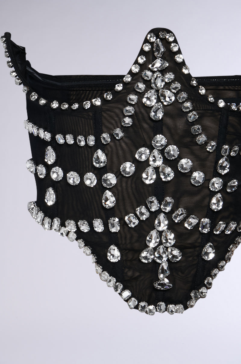 The JODIE RHINESTONE BELT is a high-waisted black sheer mesh accessory designed with an underbust style. It is embellished with large and small sparkling rhinestones arranged in a symmetrical pattern, beautifully displayed against a plain background.