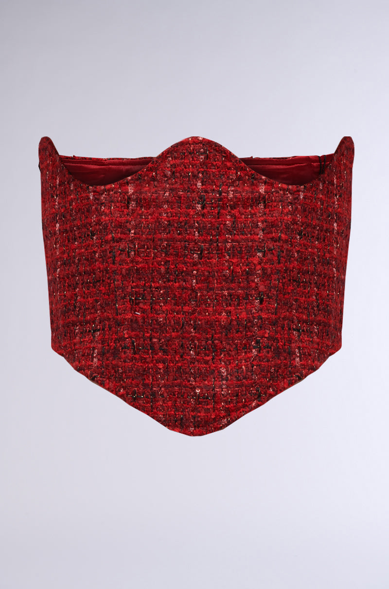 The Tweedy Underbust Corset Belt is crafted from a red, textured tweed fabric featuring a pointed, scalloped top and a smooth finish. The material has woven details with interspersed black and lighter red threads that enhance its depth. Designed to fit snugly around the waist, this corset showcases an intricate woven appearance.