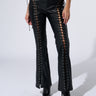 A person wearing the H-TOWN HOTTIE FAUX LEATHER LACE UP PANT, showcasing crisscrossing laces along the sides that reveal glimpses of skin, paired with black heeled boots. The ensemble is completed with a black top featuring cutouts and tie details, creating an edgy, H-Town Hottie-inspired look.