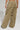 A person wearing the STEALTHY CORDUROY CARGO PANTS in high-rise, wide-legged, khaki-colored corduroy fabric, featuring multiple pockets. The pants have a casual style as the individual stands against a plain background.