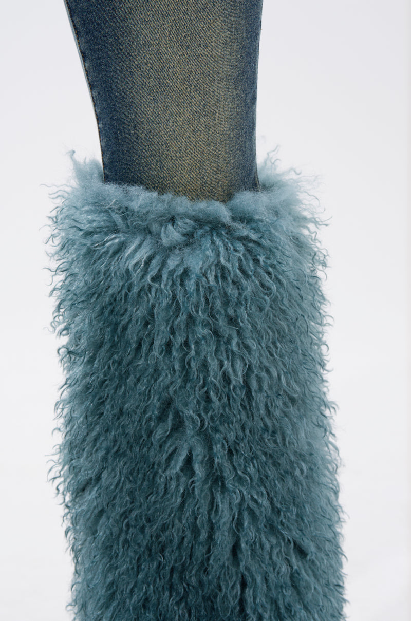 A close-up shows the SIT PRETTY FUR TRIM JEANS IN BLUE DENIM, featuring teal shaggy faux fur trim on the lower leg. The background is plain and light-colored.