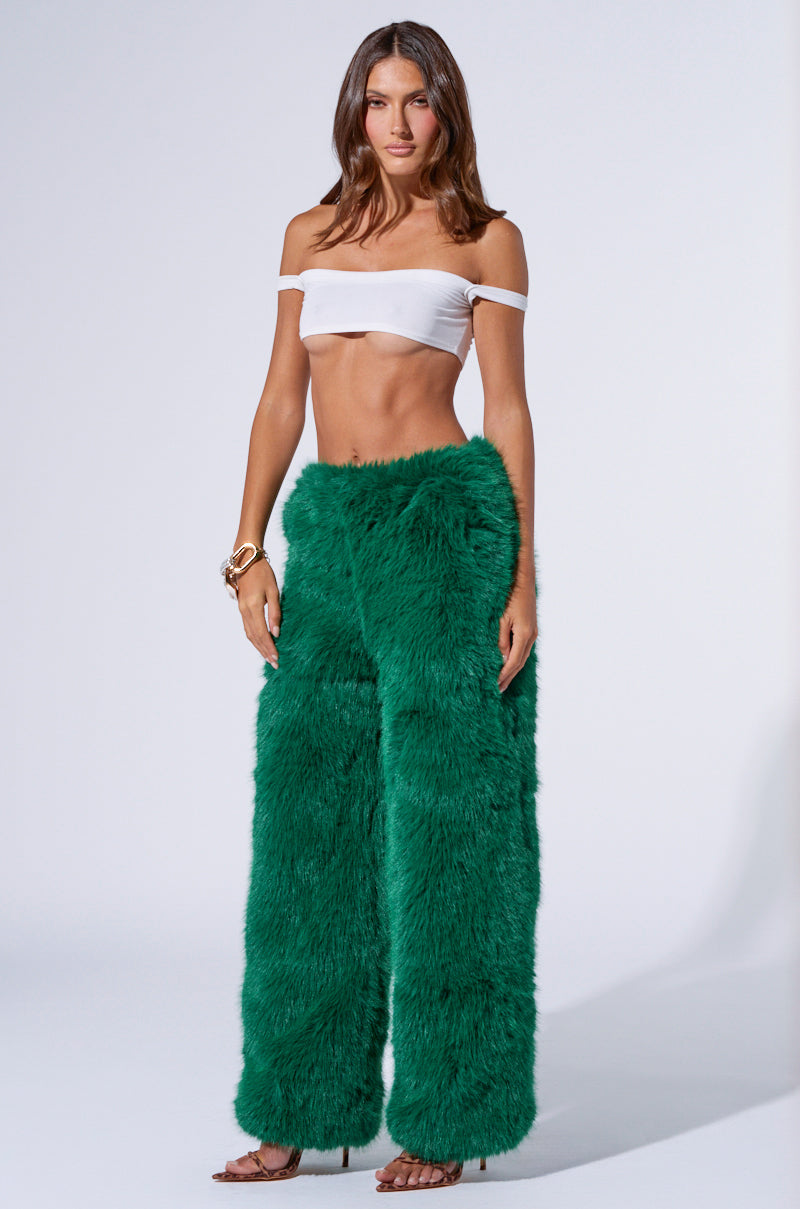 A woman stands against a plain background wearing a white off-shoulder crop top and the SEEING GREEN WIDE LEG FASHION FUR PANT. She accessorizes with bracelets and brown high-heel shoes, has long, loose brown hair, and poses with her hands relaxed by her sides.