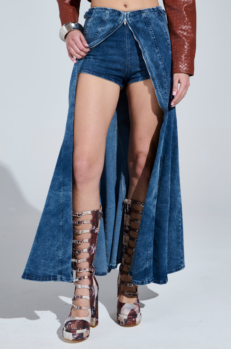 Someone is wearing the PAINTED LADY MAXI SKIRT WITH BUILT IN SHORT, paired with knee-high platform boots with multiple buckles. They are also donning a brown textured long-sleeve top and a silver bracelet on their wrist.