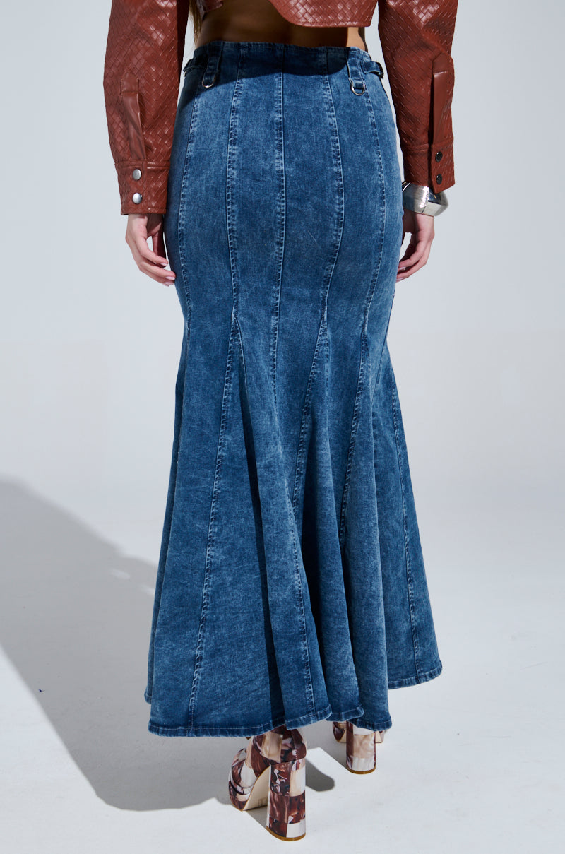 Someone is wearing a brown textured jacket with a PAINTED LADY MAXI SKIRT WITH BUILT IN SHORT that has visible seams. They are also sporting patterned high-heeled shoes against a plain and neutral background.