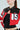 A person in a red and black ACE CROPPED GRAPHIC MOTO jacket with large white and black patches, hoop earrings, and a black top. The AKIRA Label jacket features 