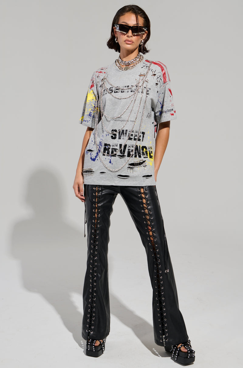 A person wearing the Sweet Revenge Distressed T-shirt in grey, coupled with black leather lace-up pants, chunky footwear, layered necklaces, and dark sunglasses, exudes confidence against a neutral background in true grunge-chic style.