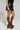 A person showcases leopard-print knee-high platform boots with a chunky heel, paired with the BACK TO THE FUTURE MINI SKIRT and a sleeveless top. Their side-facing pose highlights the outfit's details against a neutral background, adding a modern twist to this stylish ensemble.