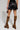 A person stands against a plain background, donning a chic windbreaker-inspired ensemble featuring the edgy 