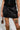 The individual is dressed in a BACK TO THE FUTURE MINI SKIRT paired with a matching top, revealing a skull tattoo on the thigh. They carry a petite leopard print bag and sport knee-high leopard print boots. The emphasis is on the lower half, highlighting the outfit's bold style and tattoo.