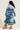 A person with long, curly hair is wearing the LIV FUR TRIM DENIM TRENCH, styled in blue denim with fur trim on the collar and cuffs. They are also wearing fur boots and holding a small handbag while standing against a plain background.