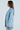 A woman stands in profile wearing a DIAMONDS DANCING DENIM BLAZER, featuring a sequined, oversized longline silhouette in light blue against a plain background. Her long, straight hair echoes the elegance of her ensemble.
