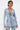 A woman models the DIAMONDS DANCING DENIM BLAZER in light blue with matching pants, accessorized with large hoop earrings and a metallic handbag, standing confidently against a plain white background.