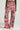 A person is sporting the STAND OUT TO FIT IN CARGO PANTS in a vibrant high-rise pink camouflage design with a wide-leg silhouette, multiple pockets, and a belt, paired with white sneakers. The lively mix of pink, black, and green patterns stands out against a plain background.