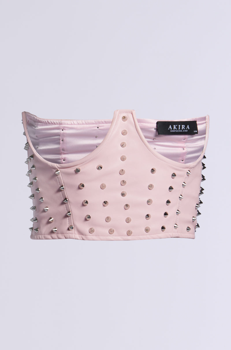 The product, "PRETTY BUT I BITE SPIKE BELT," is a pale pink faux leather studded bustier with a structured design and silver spikes on the sides. The inside features the "AKIRA" brand label against a light grey background. 0
