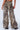 The person is showcasing the RUN AWAY SNAKE PANT, which features a high-rise waist and a wide-leg silhouette with an eye-catching brown and beige snakeskin print. This chic design includes a back pocket and pairs seamlessly with black platform shoes against a plain white backdrop.