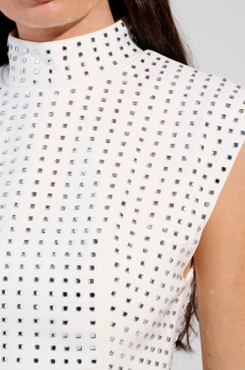 Close-up of a woman wearing the ICED OUT TOP, a sleeveless white design embellished with a grid pattern of square silver studs and sparkling rhinestones. The top is styled with a high collar against a plainly lit background.