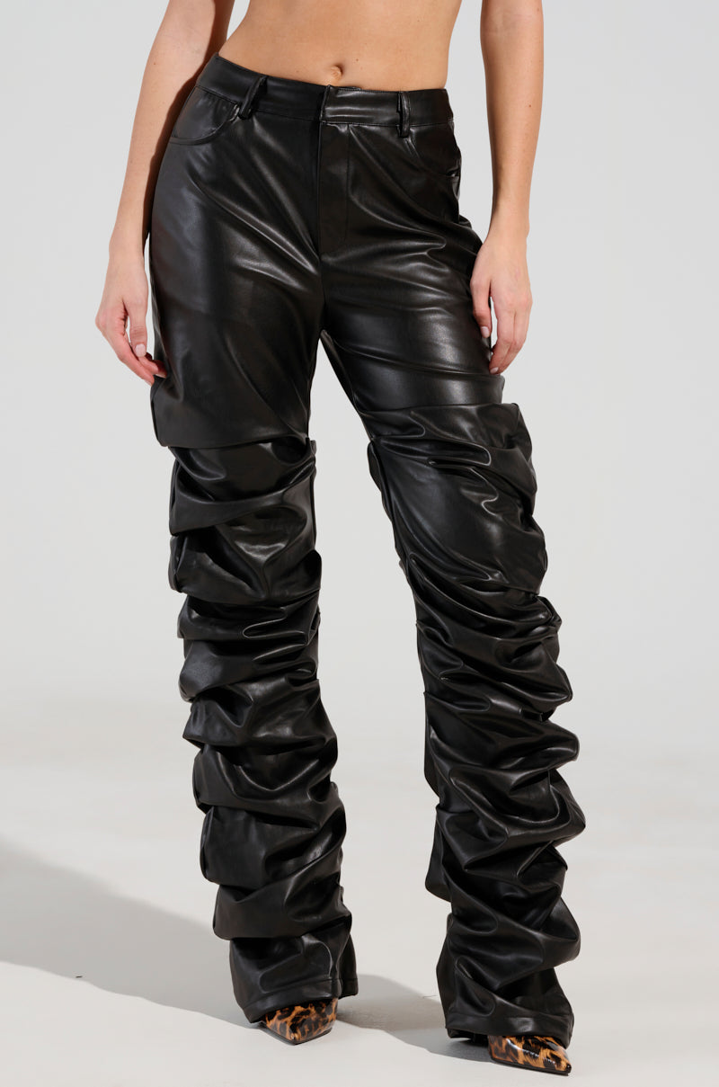 A person wearing the DOUBLE TROUBLE TROUSER, featuring high-waisted, ruched faux leather with a skinny leg silhouette, paired with pointed-toe leopard print shoes against a plain white background.