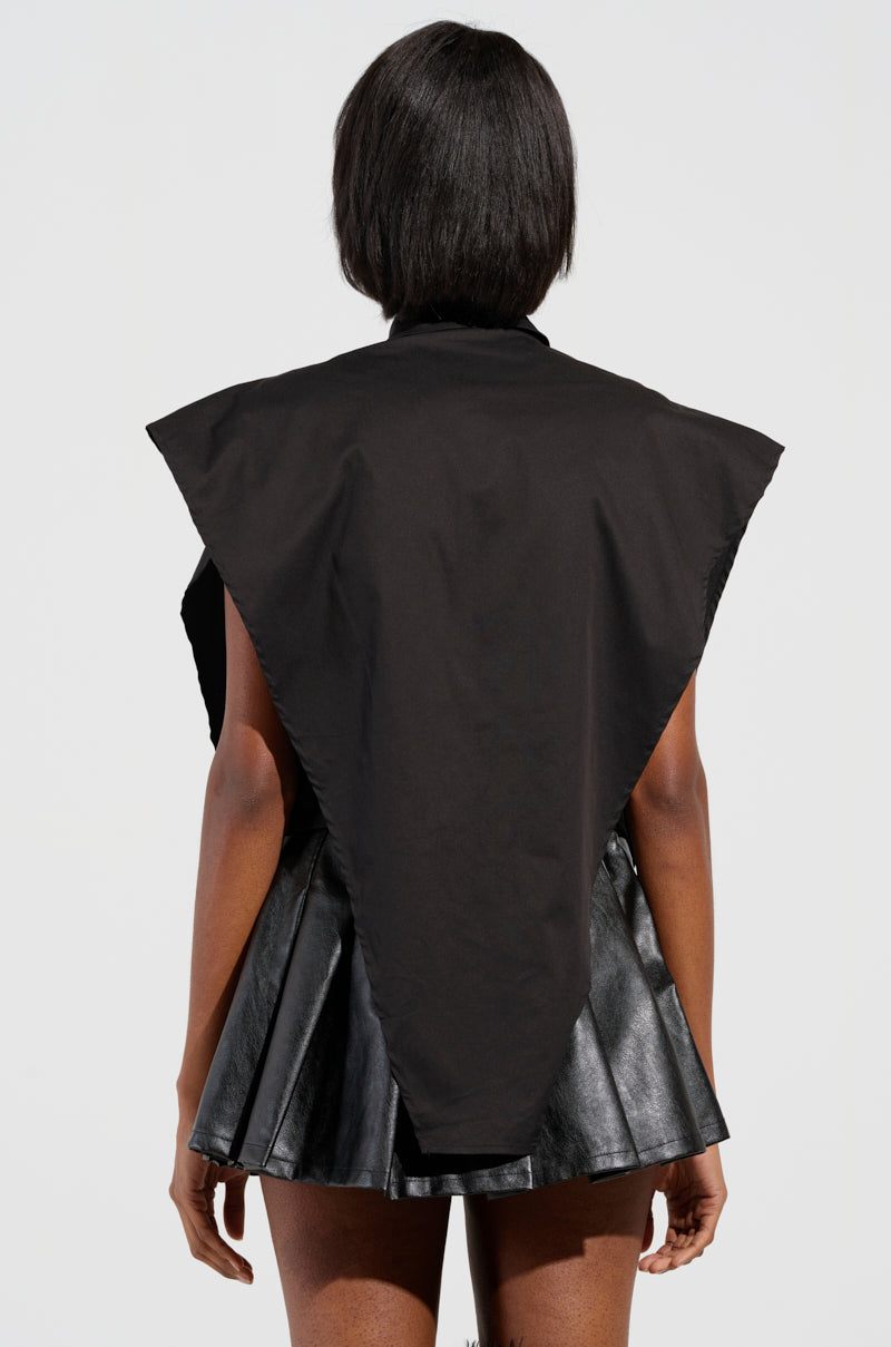 A person with short black hair is seen from behind, wearing the edgy-chic BAD GIRL ZIPPER DETAIL BUTTON DOWN SHIRT, which features triangular shoulders paired with a pleated skirt. The minimalist background emphasizes the modern design, accentuating the bold statement made by its metallic zipper detailing.