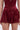A person wearing the RED HOT FLOUNCY SHORT in a rich burgundy satin with a matching top; the image is cropped from midriff to thighs.