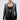A woman with slicked-back hair models the MILA EMBELLISHED BLAZER IN BLACK with silver sequin stripes, a black lace bralette, matching stretch pants, dangling earrings, and a silver clutch against a plain backdrop.