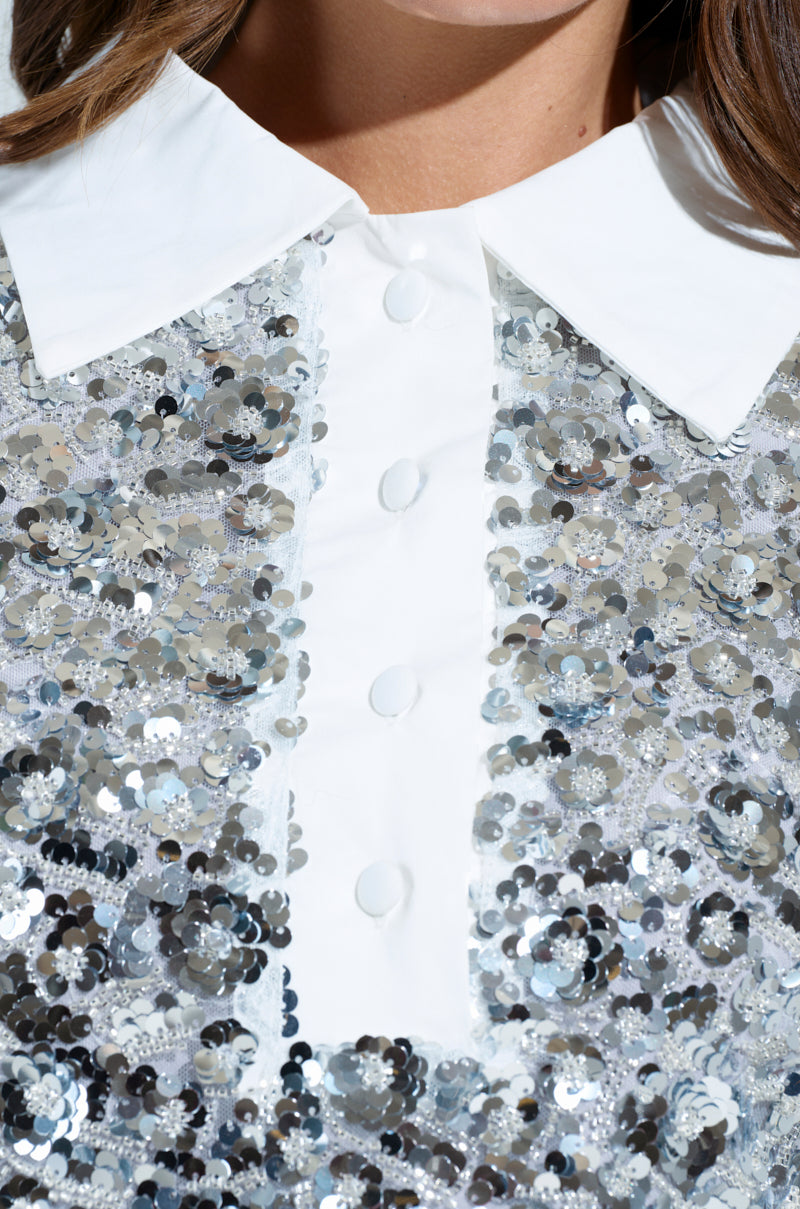 Close-up of the SO POSH BEADED SEQUIN SHIRT DRESS, showcasing a white collared shirt with shiny silver sequins and delicate bead embellishments, featuring white buttons. The mesh base makes the fabric sparkle for a glamorous, eye-catching effect.