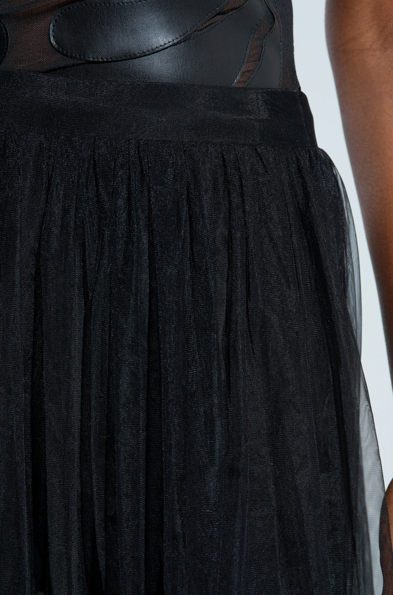 A close-up of someone wearing the TRY ME MAXI SKIRT paired with a sleek black leather corset against a neutral background. The lightweight, semi-transparent tulle fabric offers a stunning contrast to the structured leather.