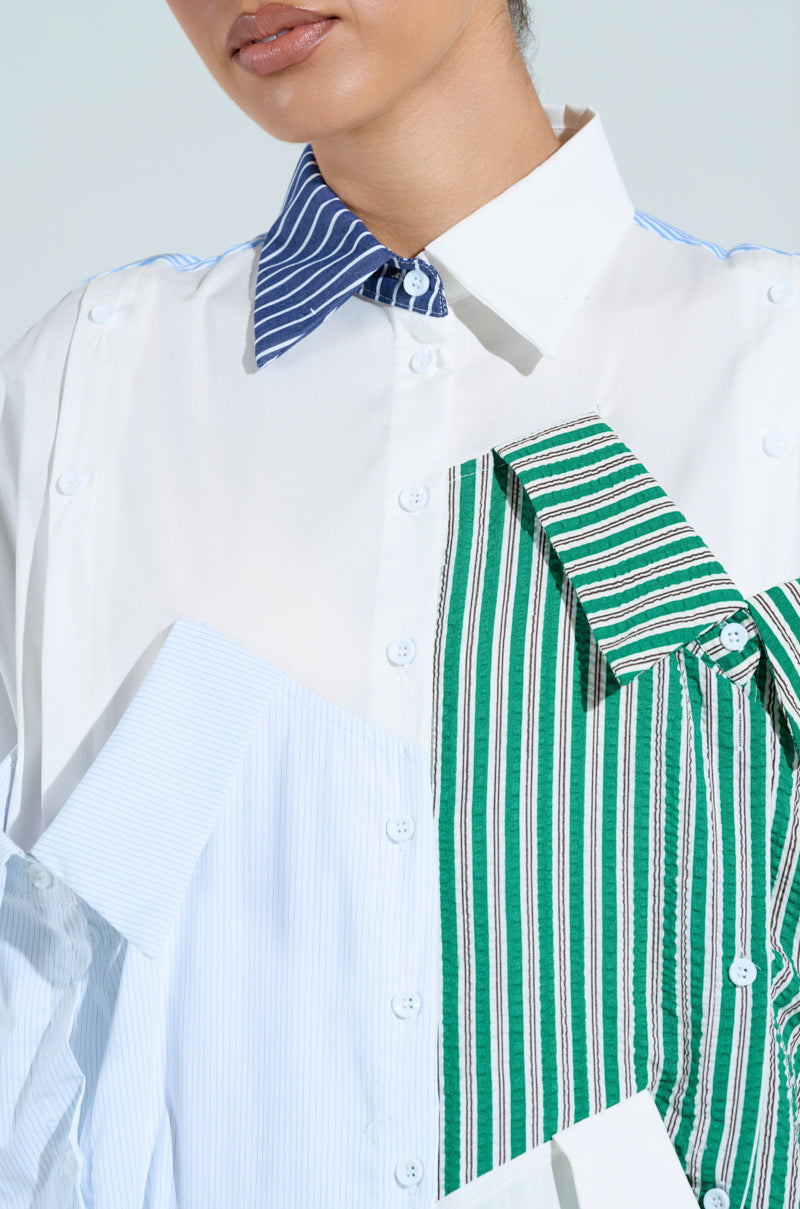 Someone is wearing the NOT YOUR BOYFRIENDS SHIRT MAXI DRESS, a creatively designed button-up with overlapping blue, green, and white striped panels. Made on a poplin base, it features an oversized silhouette and different colored collars for an artistic, modern flair.