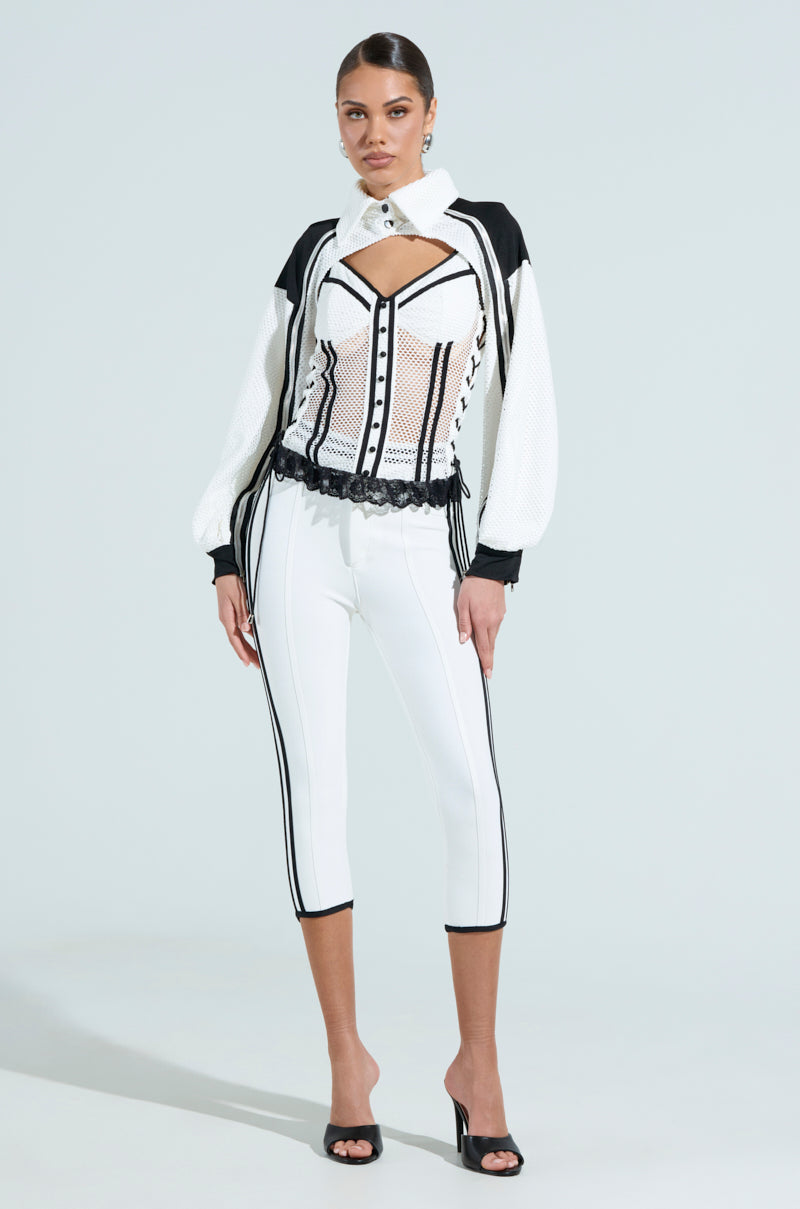 Dressed in sporty-chic elegance, they flaunt the VIVI JERSEY CORSET with white pants accented by black stripes, sleek high heels, and an updo against a light backdrop. 6