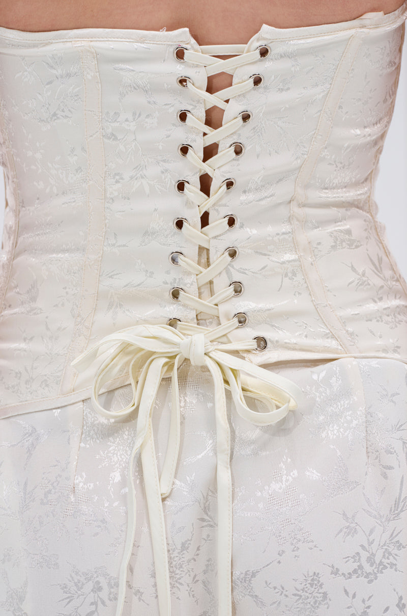 Close-up of the back of the DAISY DOVE JACQUARD CORSET with floral jacquard patterns, cream ribbon lacing tied at the waist, worn over a matching satin skirt and finished with delicate boning for structure.