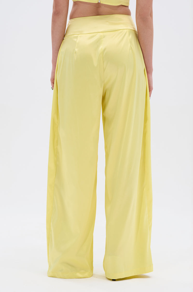 A person, seen from the back against a white background, wears loose-fitting, high-waisted ELECTRIC SATIN TROUSER in high-sheen satin with adjustable belted accents.