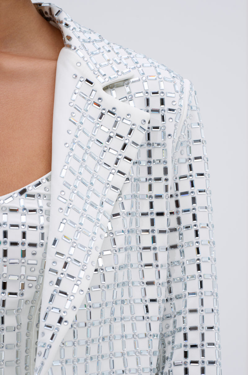Close-up of the WHITE HOT EMBELLISHED BLAZER with a notch lapel collar and mirrored grid embellishments, worn over a matching top. The reflective design catches light for a sparkling effect.