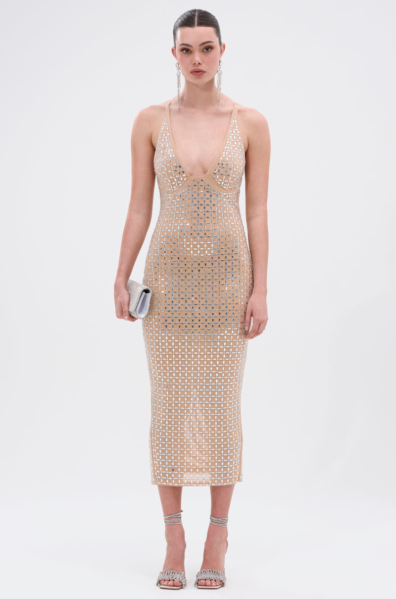 A woman stands in the QUEEN OF EVERYTHING MIDI DRESS, a sheer double-lined mesh design with mirrored embellishments, styled with a silver clutch, silver high-heeled sandals, drop earrings, and her hair tied back against a white background. 2