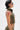A person with short dark hair wears large sunglasses and the DARIA STUDDED CAMO SIDE LACE TOP, paired with a matching skirt. Bold style shines with edgy camo details, lace-up sides, and dramatic pink arm art for a chic statement look.