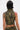A person with short black hair is shown from the back wearing the DARIA STUDDED CAMO SIDE LACE TOP, featuring studs and lace-up sides. Their right arm displays tattoos and a red striped tattoo is visible on their left shoulder.