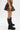 A person models the DARIA STUDDED CAMO MINI SKIRT featuring gold-tone studs, paired with tall black combat boots, against a plain white background; only the lower body is shown.