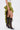Wearing the CLAIRE HIGH LOW RUFFLE SKIRT in olive green, a white side-laced top, and black lace-up knee-high stiletto boots, a person stands against a plain white background.