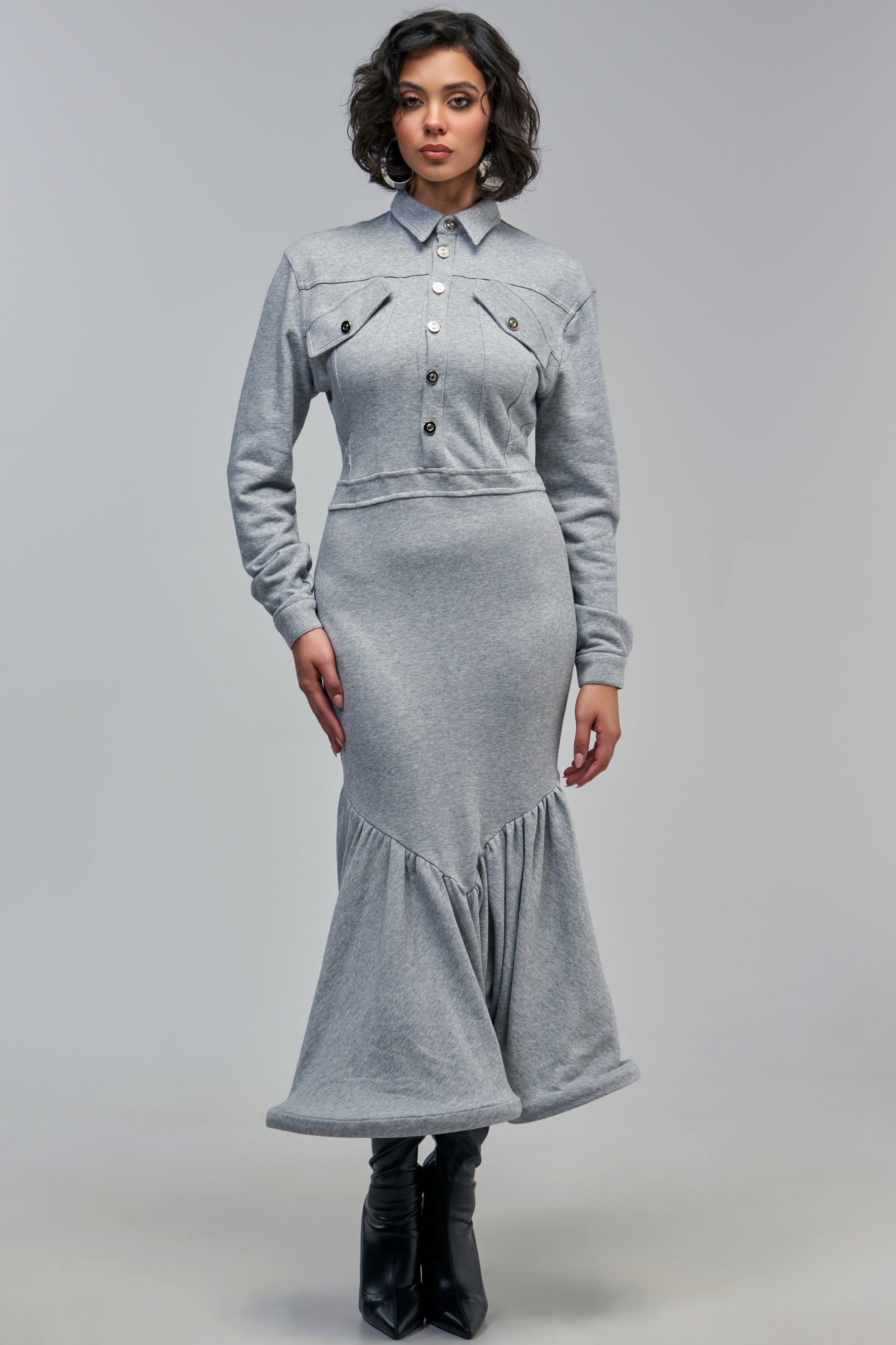 A person wearing a heather grey COMFY YET CUTE LONG SLEEVE SCUBA MAXI DRESS with a button-down collar, chest pockets, and a flared hem, paired with black boots.