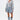 A woman poses against a white background wearing the FELT CUTE SWEATSHIRT DENIM MINI DRESS. She sports wet-look hair, visible tattoos, and completes her streetwear-inspired look with knee-high denim boots with white laces.