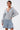 A woman stands confidently with one hand on her hip, modeling the FELT CUTE SWEATSHIRT DENIM MINI DRESS—a stylish blend of laid-back loungewear and streetwear—against a plain white background.