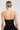 Rear view of a blonde-haired person in a bun wearing the LADY FRIEND CORSET, a strapless black dress with a curve-hugging silhouette and back zipper. The plain white background accentuates the elegant simplicity of their style.