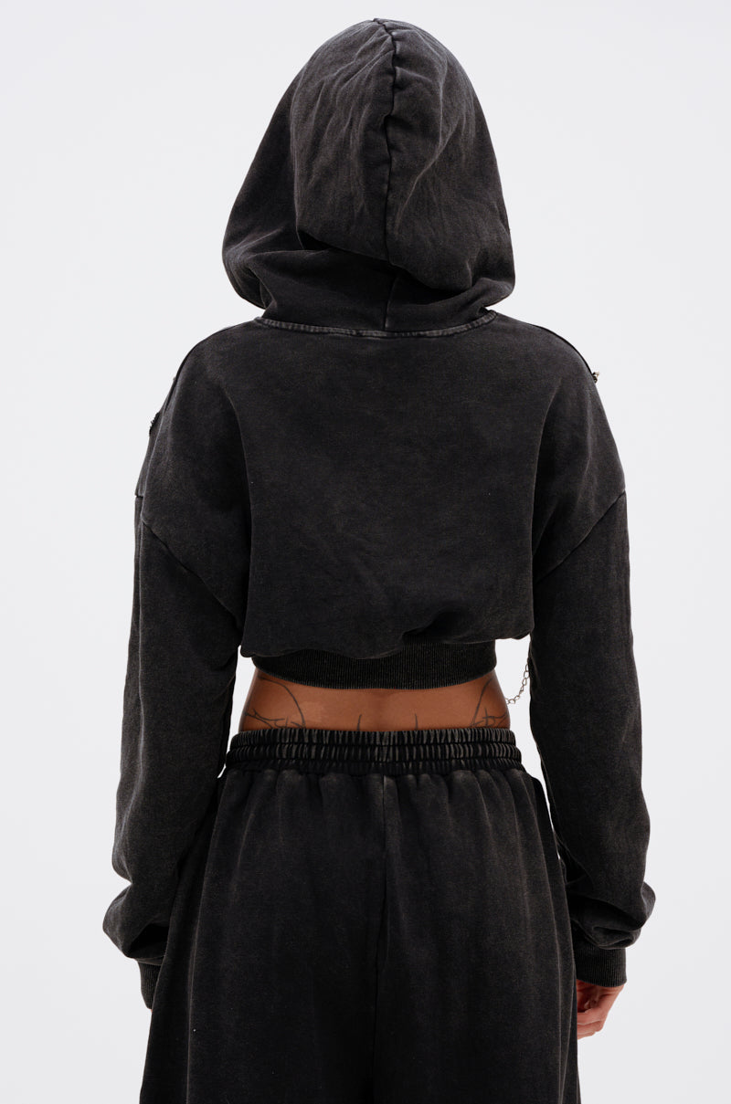 A person shown from the back on a plain white background wears the LUCKY ELEVEN CHAIN CROP SWEATSHIRT in black with the hood up, paired with loose matching black pants. 4