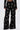 A person wears the OLD FLAME EMBELLISHED TROUSER IN BLACK—high-rise, wide-leg pants featuring clustered faux pearl embellishments—while standing against a plain white background.